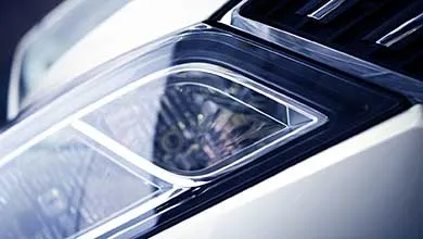 Angled close-up of a modern car's sleek headlight with clear casing.