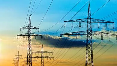 A large offshore oil rig with steel lattice towers and cranes, set against a partly cloudy blue sky.