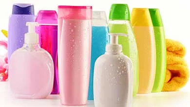 Assorted colorful plastic bottles and pump containers arranged together, representing cosmetic and personal care packaging.