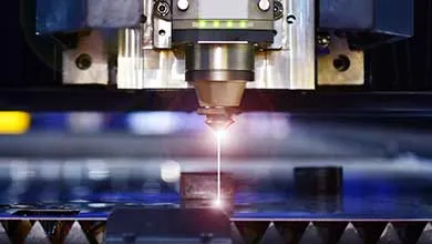 Close-up of an industrial laser cutter emitting a bright, thin beam as it cuts through metal.