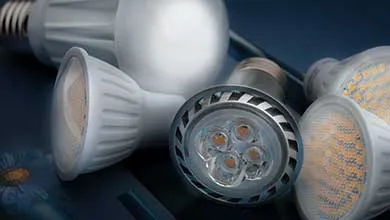 Close-up of assorted LED light bulbs, including spotlight and frosted types, scattered on a dark surface.