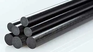 Close-up of stacked black carbon fiber rods on a white reflective surface.