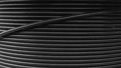 Close-up of tightly wound black filament in horizontal lines, with one strand crossing diagonally on top.