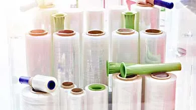 Clear stretch film rolls in various sizes, some with blue or green plastic dispensers attached.