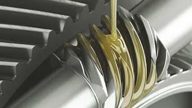 Close-up of golden lubricant being poured onto interlocking metal gears.