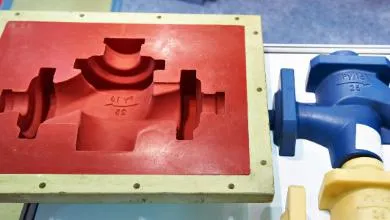 A red rectangular pipe valve mold is shown beside a finished blue valve and a partially completed yellow valve.