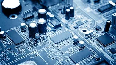 Close-up of a computer circuit board with microchips and capacitors illuminated by blue light.