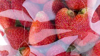 Close-up of bright red strawberries inside a clear plastic clamshell container.